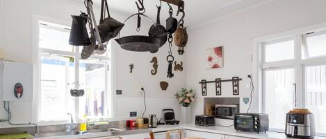 A modern kitchen with hanging pots, a sink, a microwave, and a toaster.