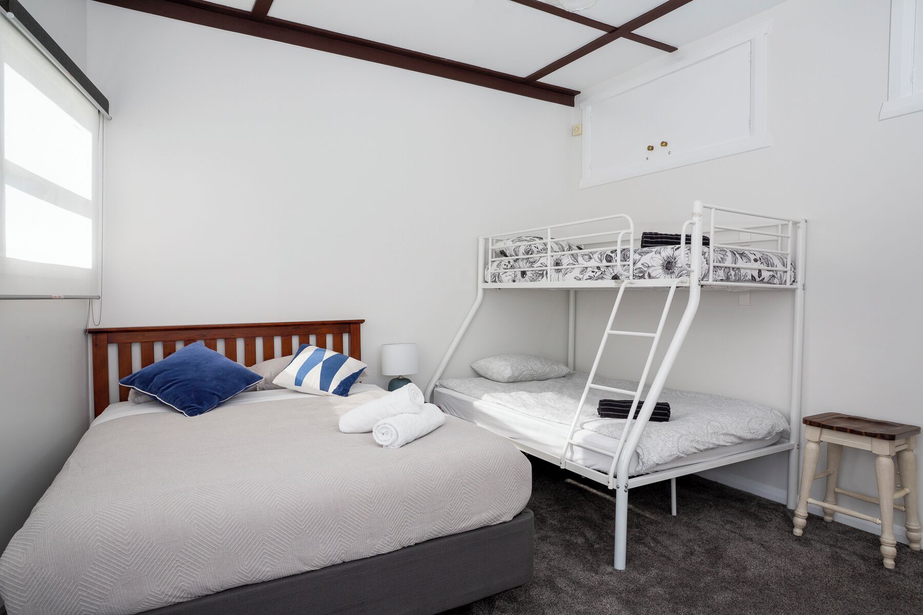 A bunk bed with a wooden headboard, a bedside table, and a lamp.