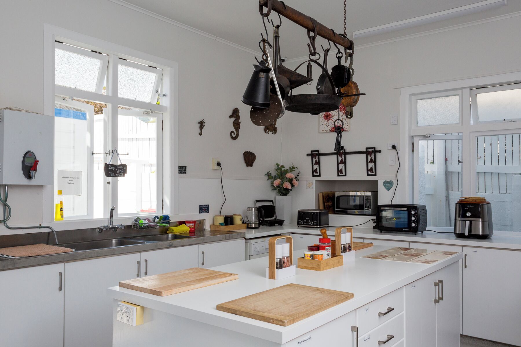 Une cuisine moderne avec des meubles blancs, un îlot central en bois et divers appareils électroménagers, notamment un four à micro-ondes et un grille-pain.