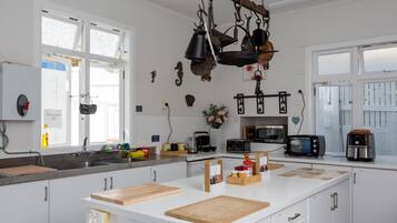 Une cuisine moderne avec des meubles blancs, un îlot central en bois et divers appareils électroménagers, notamment un four à micro-ondes et un grille-pain.