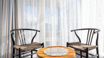 Two wicker chairs with cushioned seats and backs, positioned around a round wooden table with a patterned table runner.