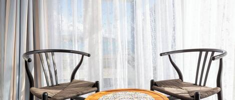 Two wicker chairs with cushioned seats and backs, positioned around a round wooden table with a patterned table runner.