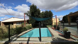Une piscine rectangulaire à l’eau d’un bleu limpide, bordée d’une margelle en briques.