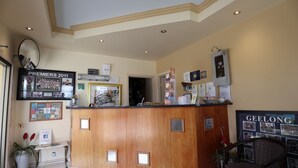 Un espace d’accueil avec un comptoir en bois, un tableau d’affichage et une photo encadrée d’un événement sportif.