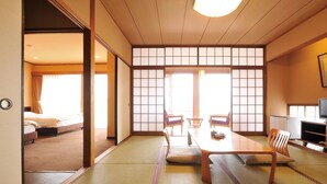 A traditional Japanese room with tatami flooring, a low table with cushions, sliding doors, and a television. - Miyahama Onsen Miyahama Grand Hotel (Hatsukaichi)