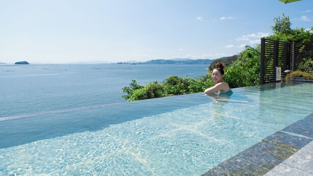 A clear infinity pool with a view of the sea and distant land. - Miyahama Onsen Miyahama Grand Hotel (Hatsukaichi)