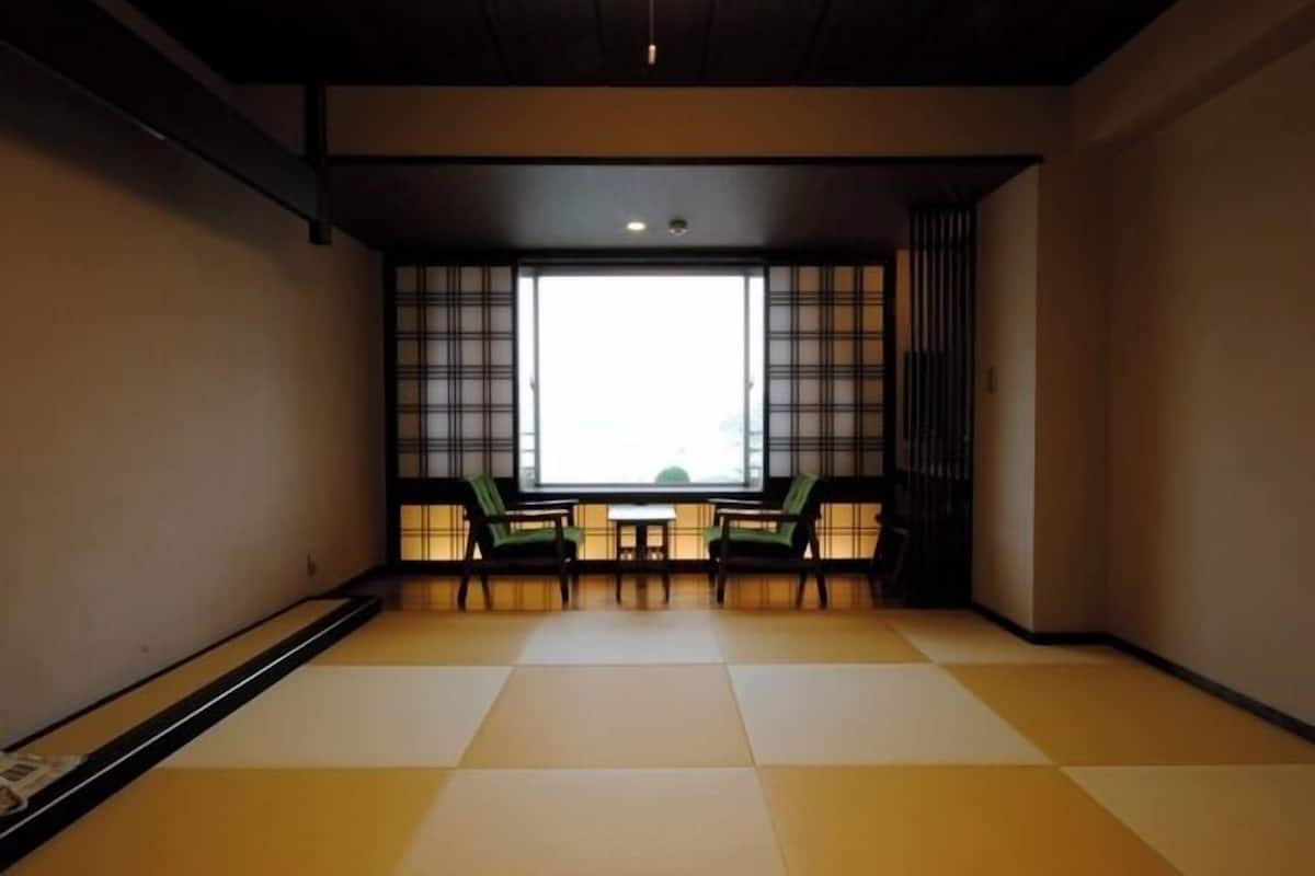 A tatami mat room with a sliding door, a small table, and two chairs.