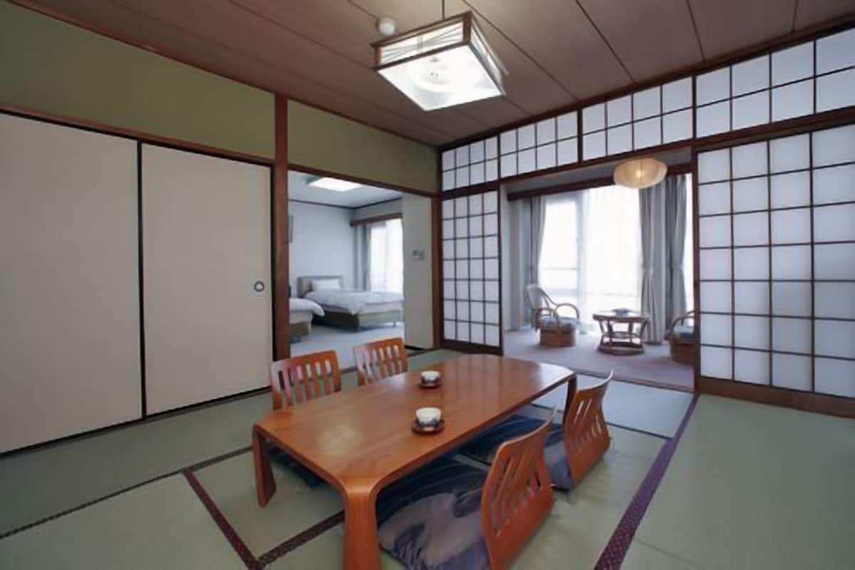 A traditional Japanese-style room with tatami flooring, a wooden dining table with chairs, and sliding shoji doors.