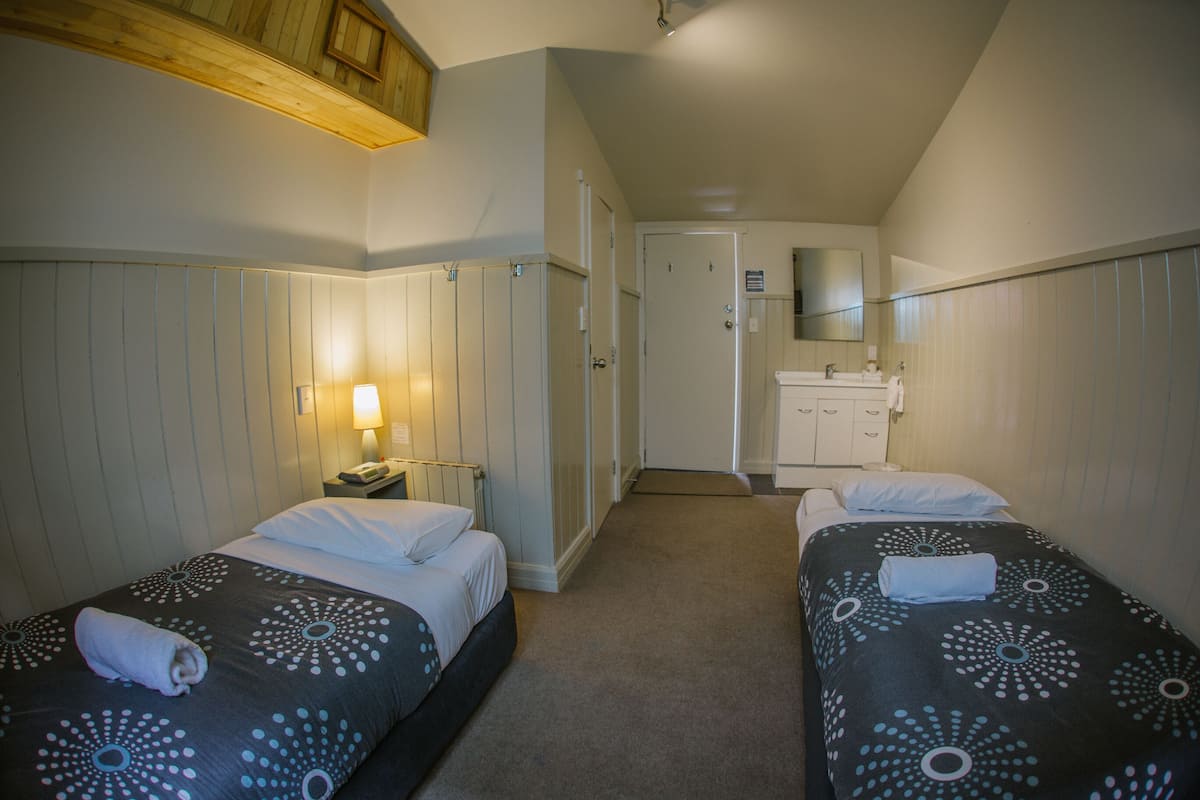 A hotel room with two beds, a bathroom, and a small sitting area.