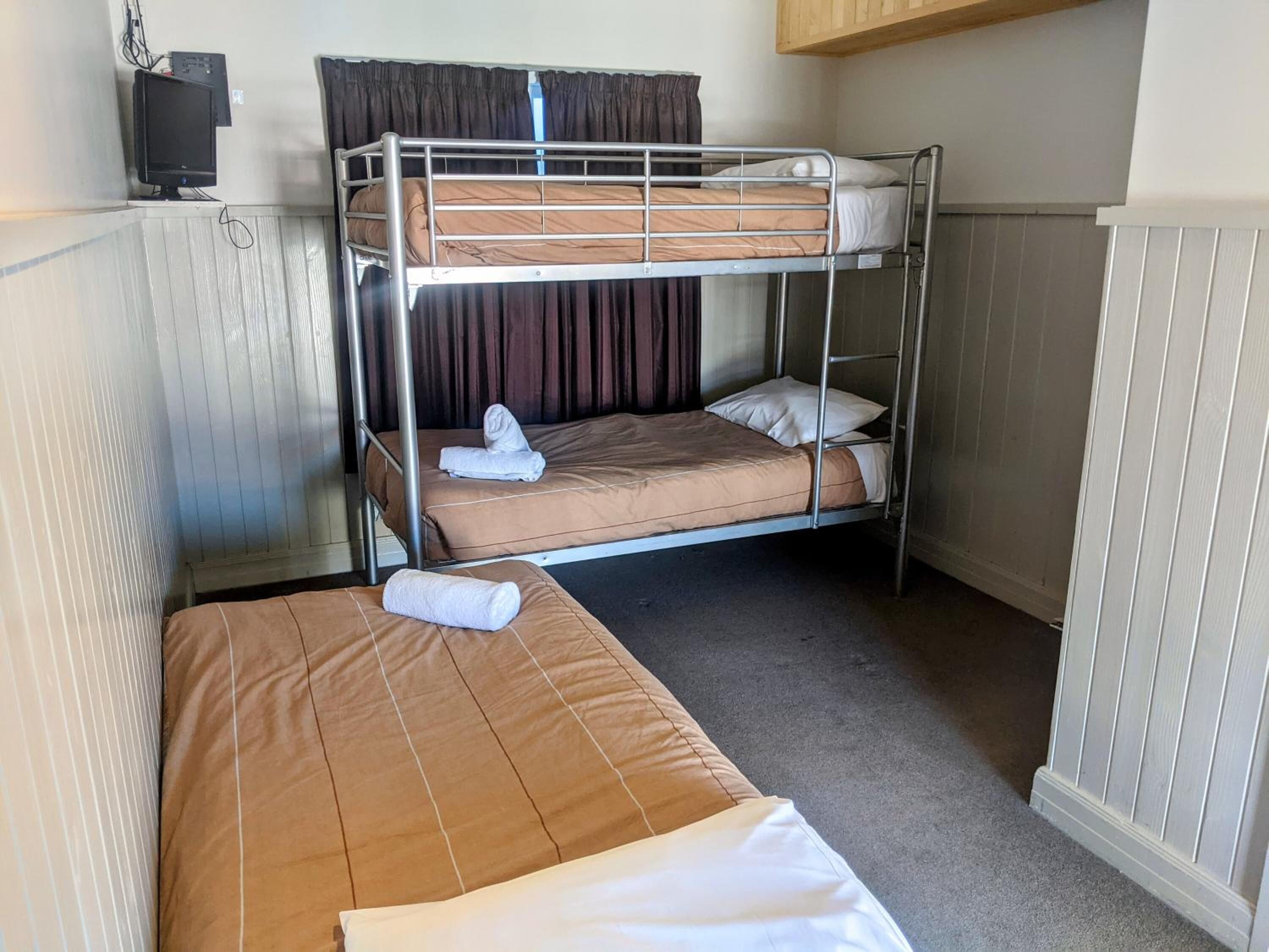 Een slaapkamer met stapelbedden, een kleine televisie en een radiator.