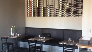 A restaurant with a chandelier, black cushioned seating, and a wall displaying wine bottles. - The White Swan Country Hotel (Greytown)