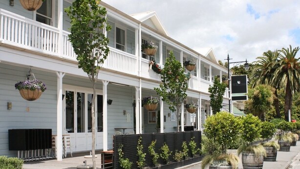 A two-story building with a balcony, potted plants, and hanging flower baskets. - The White Swan Country Hotel (Greytown)