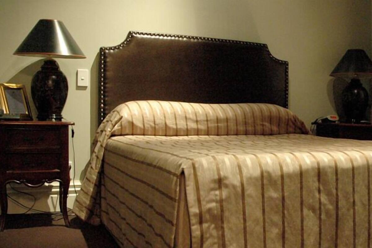A neatly made bed with striped bedding, a dark headboard, and two bedside tables with lamps.