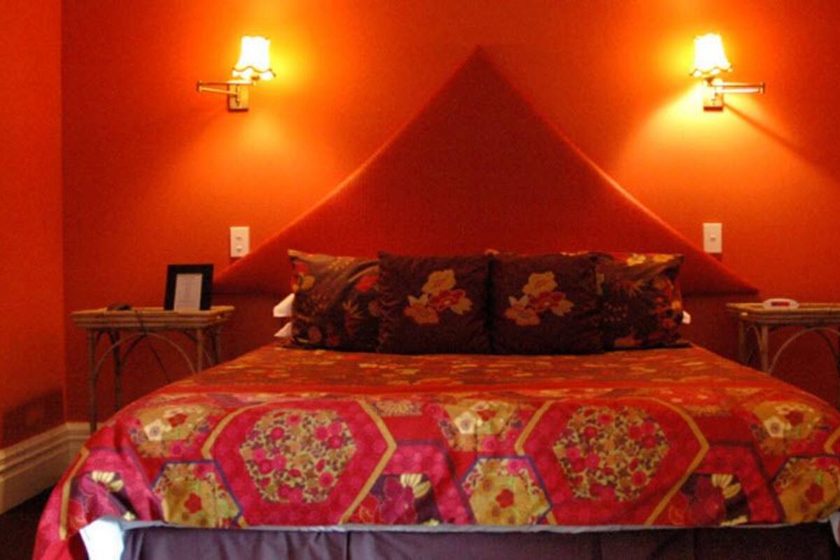 A room with a bed, two nightstands, and wall-mounted lamps.