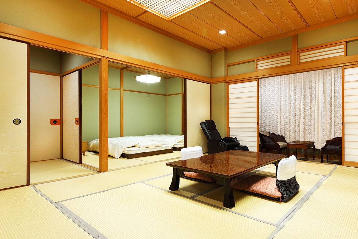 A traditional Japanese room with tatami flooring, a low table, chairs, and sliding doors.