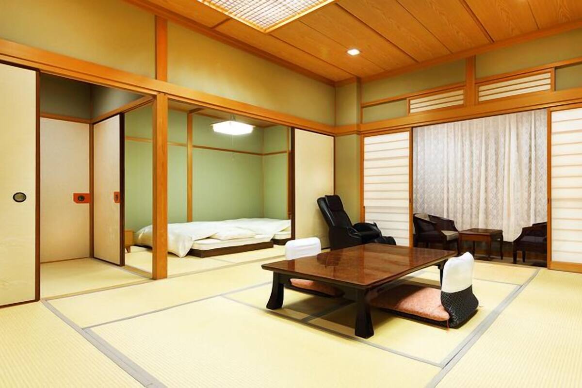 A traditional Japanese room with tatami flooring, a low table, chairs, and sliding doors.