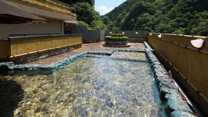 A traditional Japanese onsen with clear water, stone flooring, bamboo fences, and a mountainous backdrop. - Ryokan Yubara International Tourist HOT (MANIWA SHI)