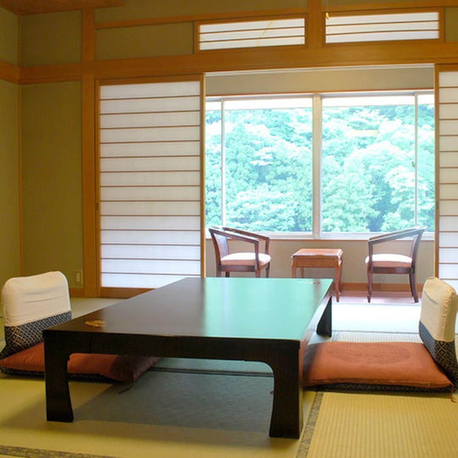 A traditional Japanese room with tatami flooring, a low table, and two chairs.
