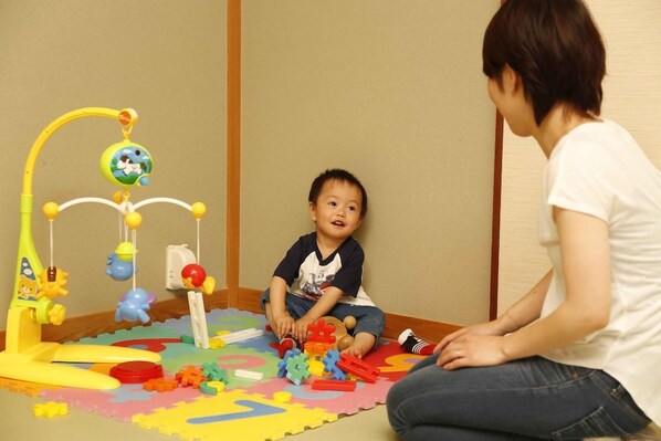 A child playing with toys on a colorful play mat. - Ryokan Yubara International Tourist HOT (MANIWA SHI)