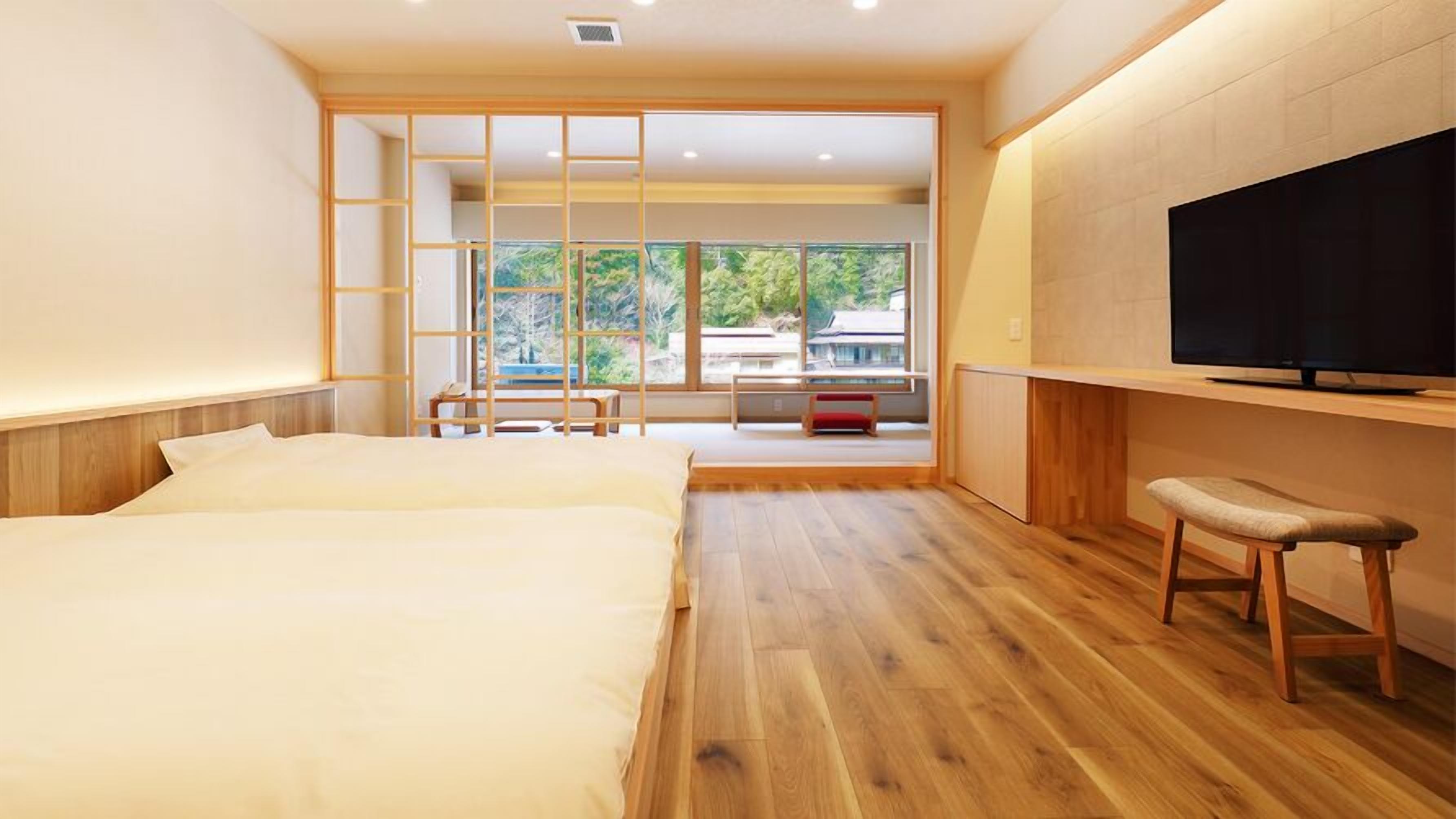 A modern hotel room with a large bed, a TV, and a view of the outdoors.