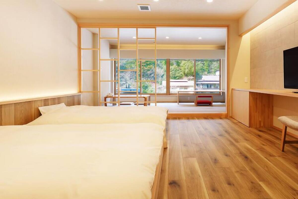 A modern hotel room with a large bed, a TV, and a view of the outdoors.