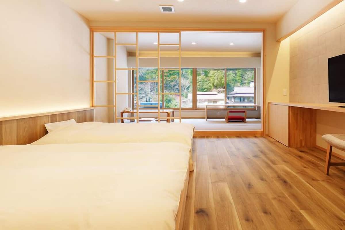 A modern hotel room with a large bed, a TV, and a view of the outdoors.