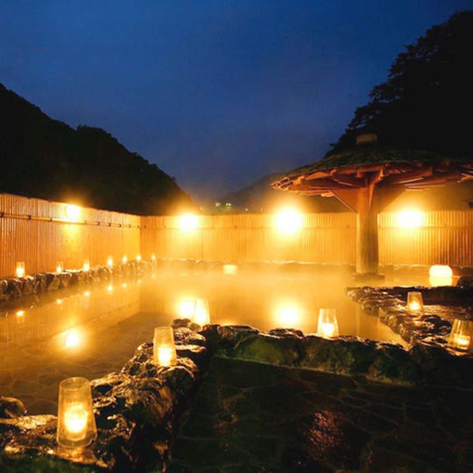 A hot spring bath area with stone seating and candles.
