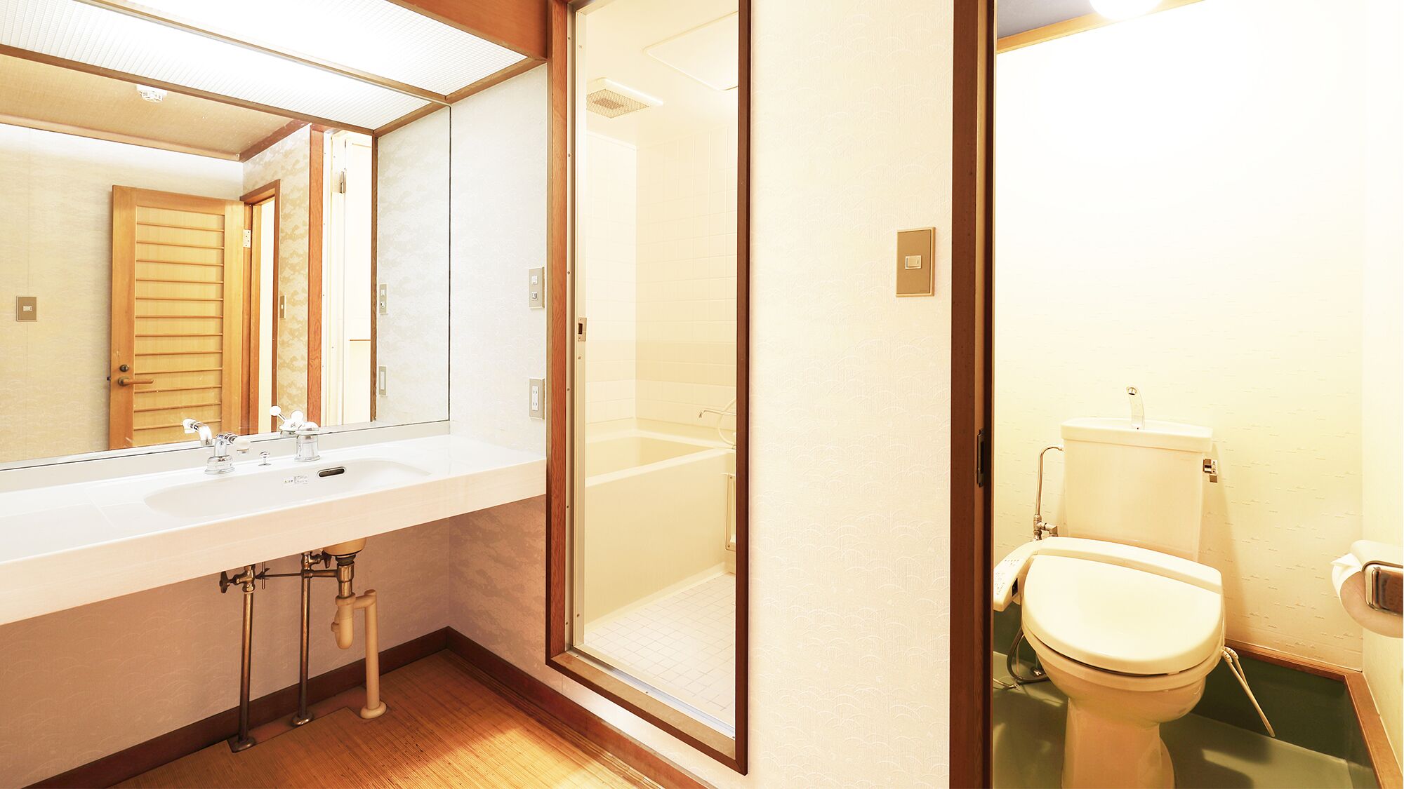 A bathroom with a large mirror, a sink, a toilet, and a shower area.
