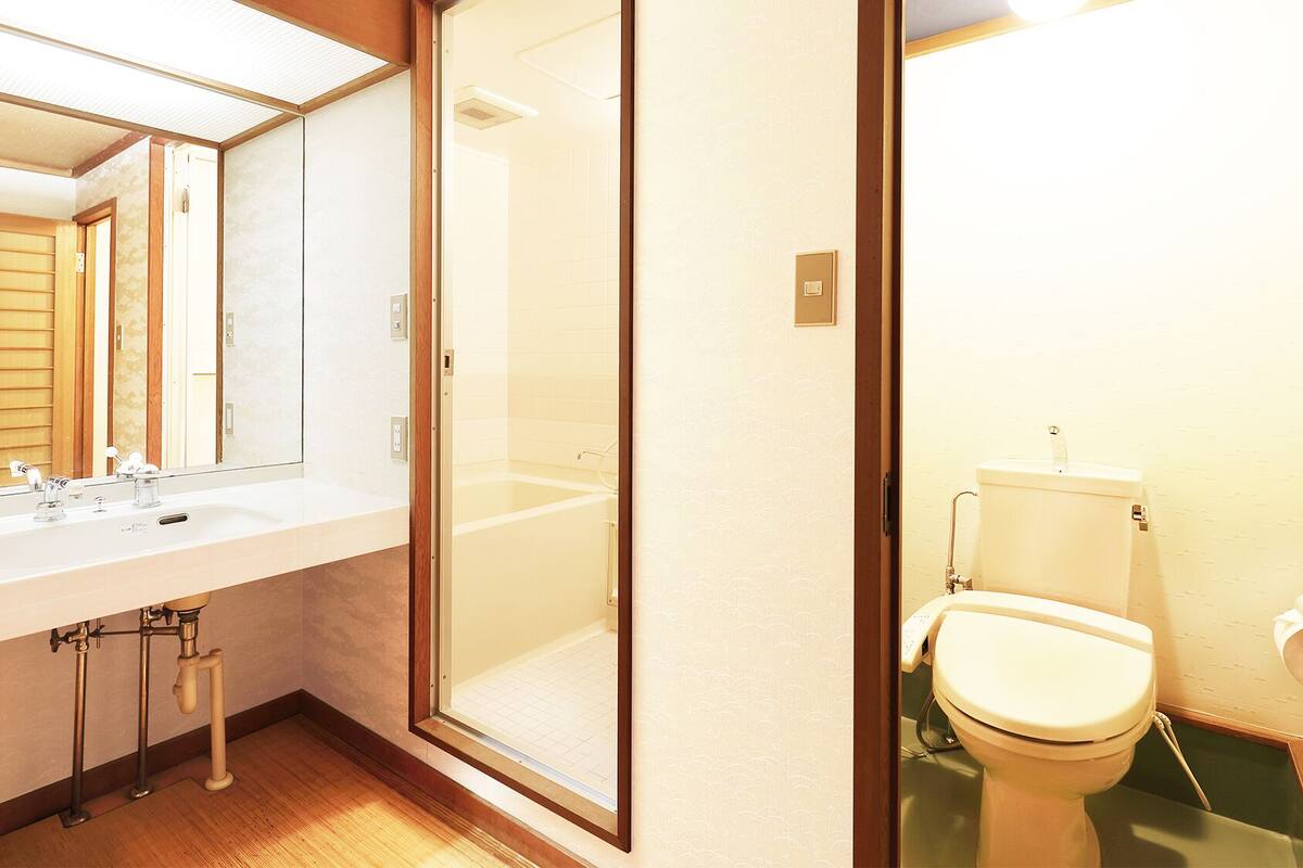 A bathroom with a large mirror, a sink, a toilet, and a shower area.