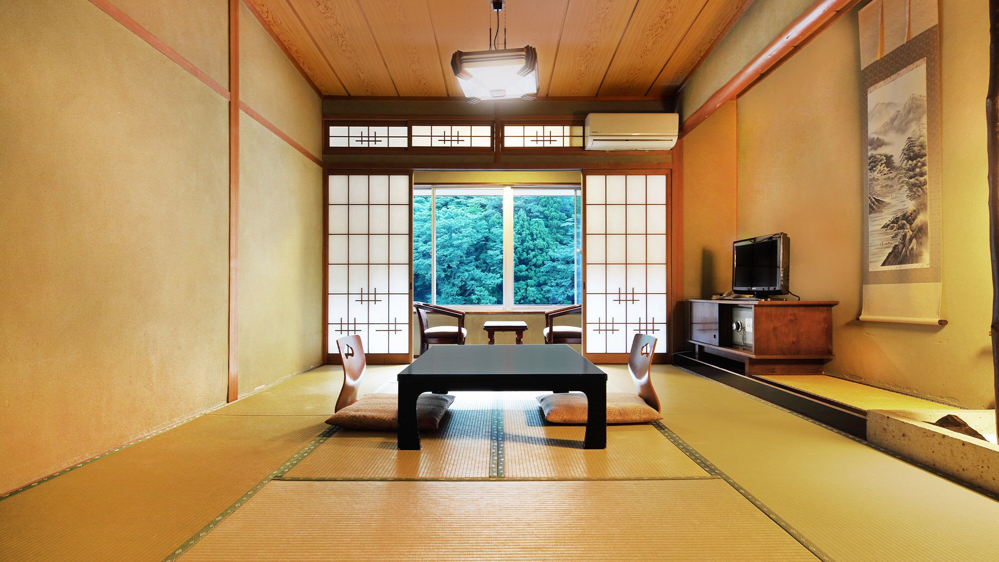 A tatami mat room with a futon bed, sliding shoji doors, a television, and a painting on the wall.