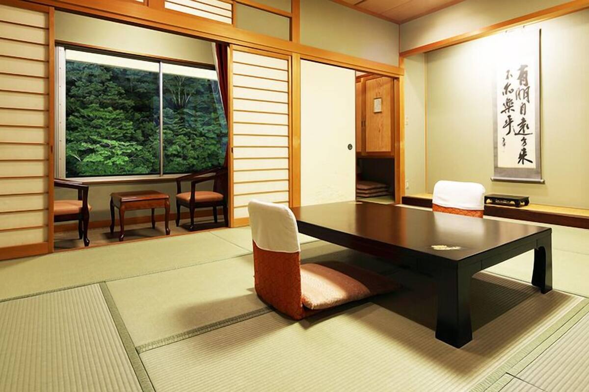 A traditional Japanese-style room with tatami flooring, a low table, and sliding doors.