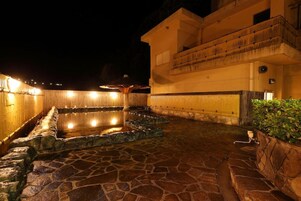 Un espacio al aire libre con piso de piedra, una piscina, rodeado de muros y un edificio con balcón.