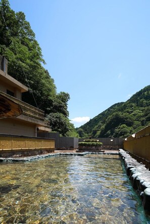 A clear outdoor pool area with a wooden deck, surrounded by buildings and a mountainous backdrop. - Ryokan Yubara International Tourist HOT (MANIWA SHI)