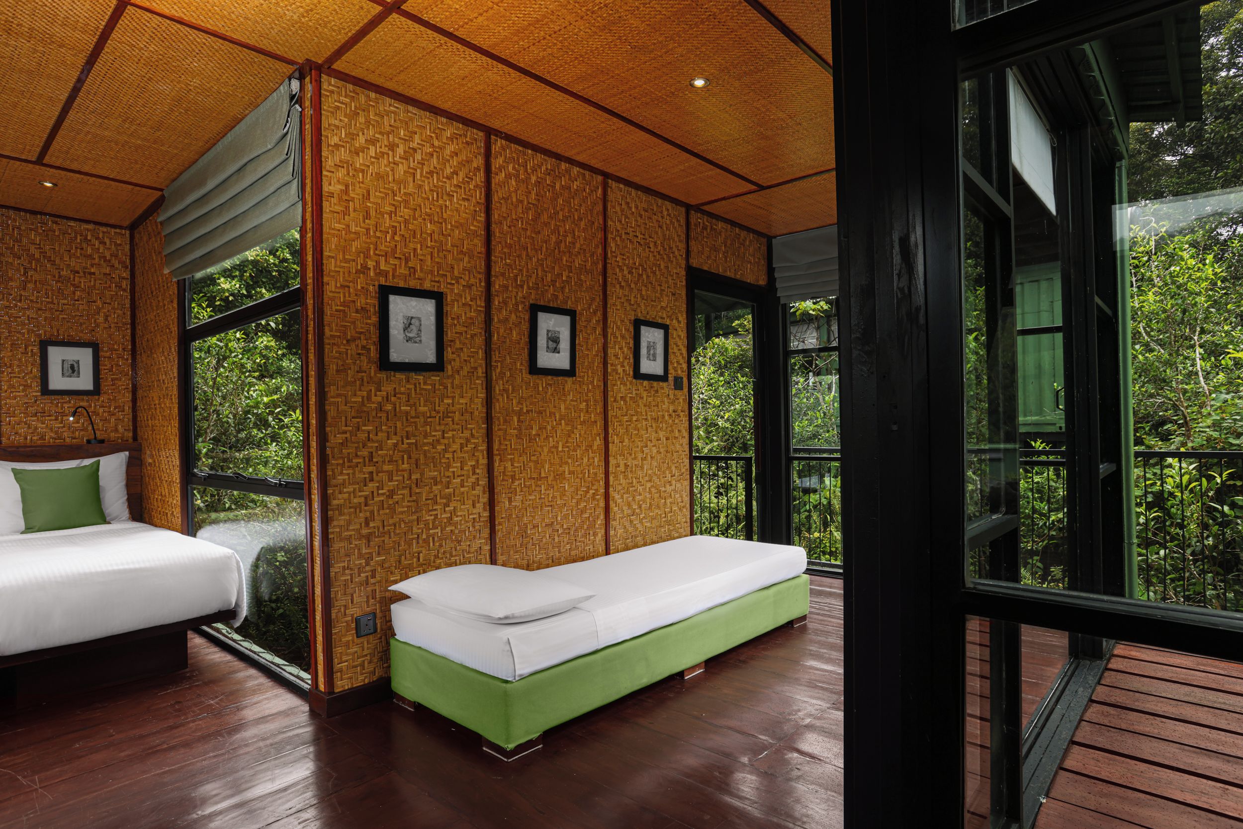 Een kamer met twee bedden, een groene bank en wanddecoraties in lijsten.