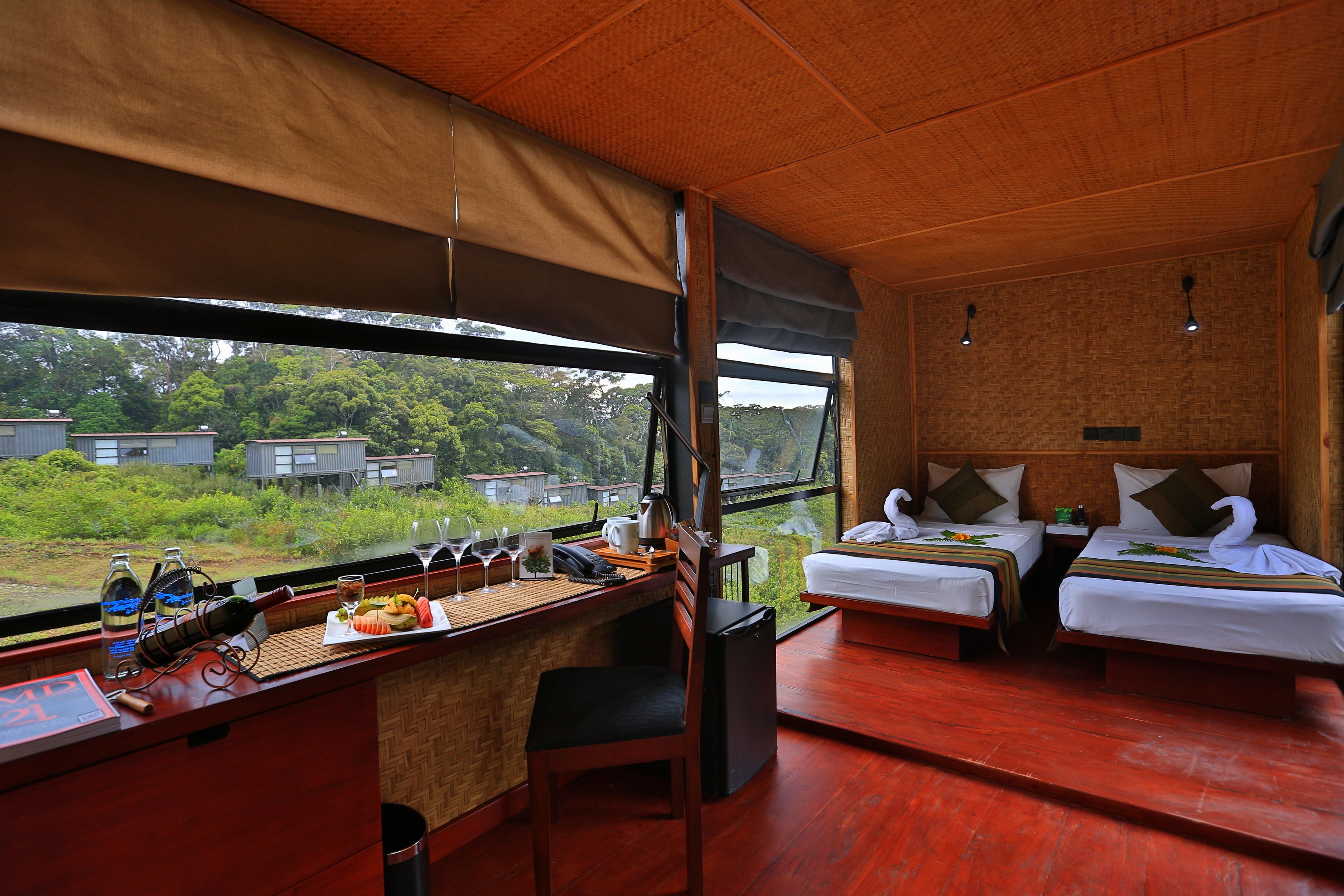 A room with two beds, a desk with a computer, and a view of the outdoors.