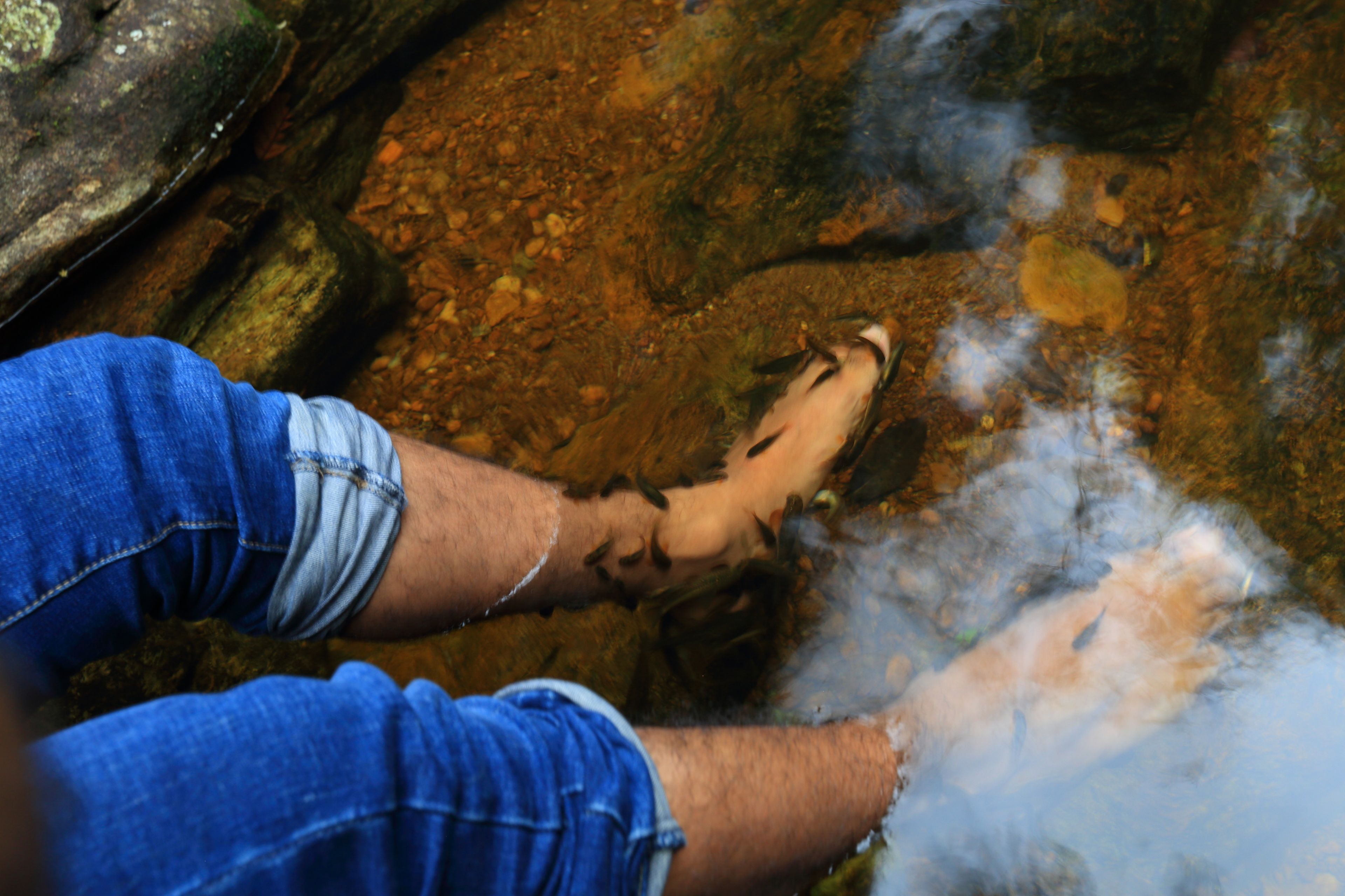 A person's foot in a stream with water flowing around it.