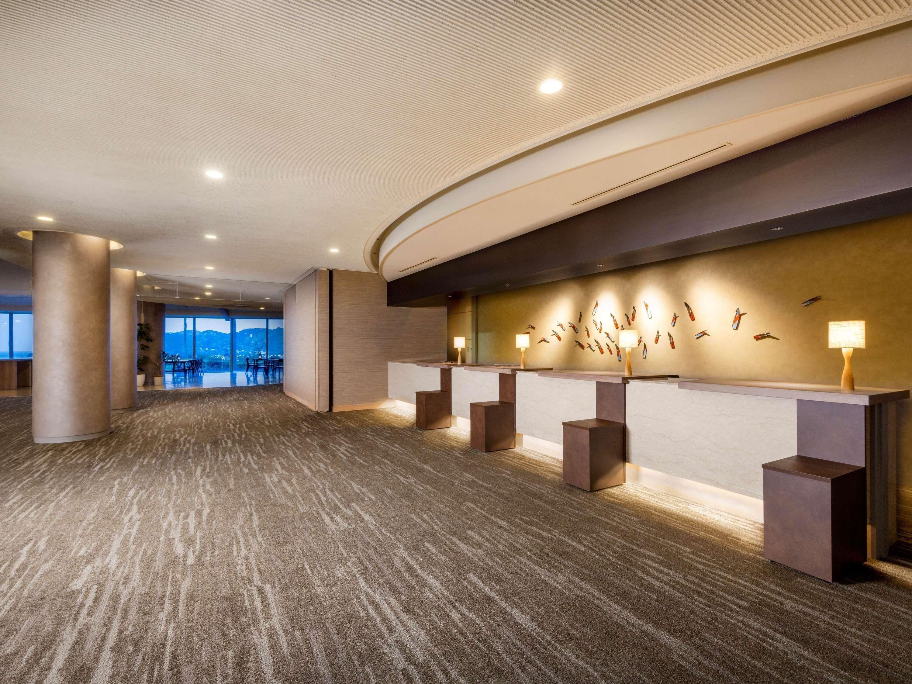 A spacious lobby with a reception desk, large pillars, and a wall with a bird mural.