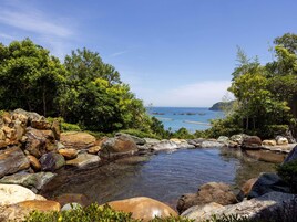 Un paisaje natural con vista despejada al mar, rodeado de rocas y abundante vegetación.