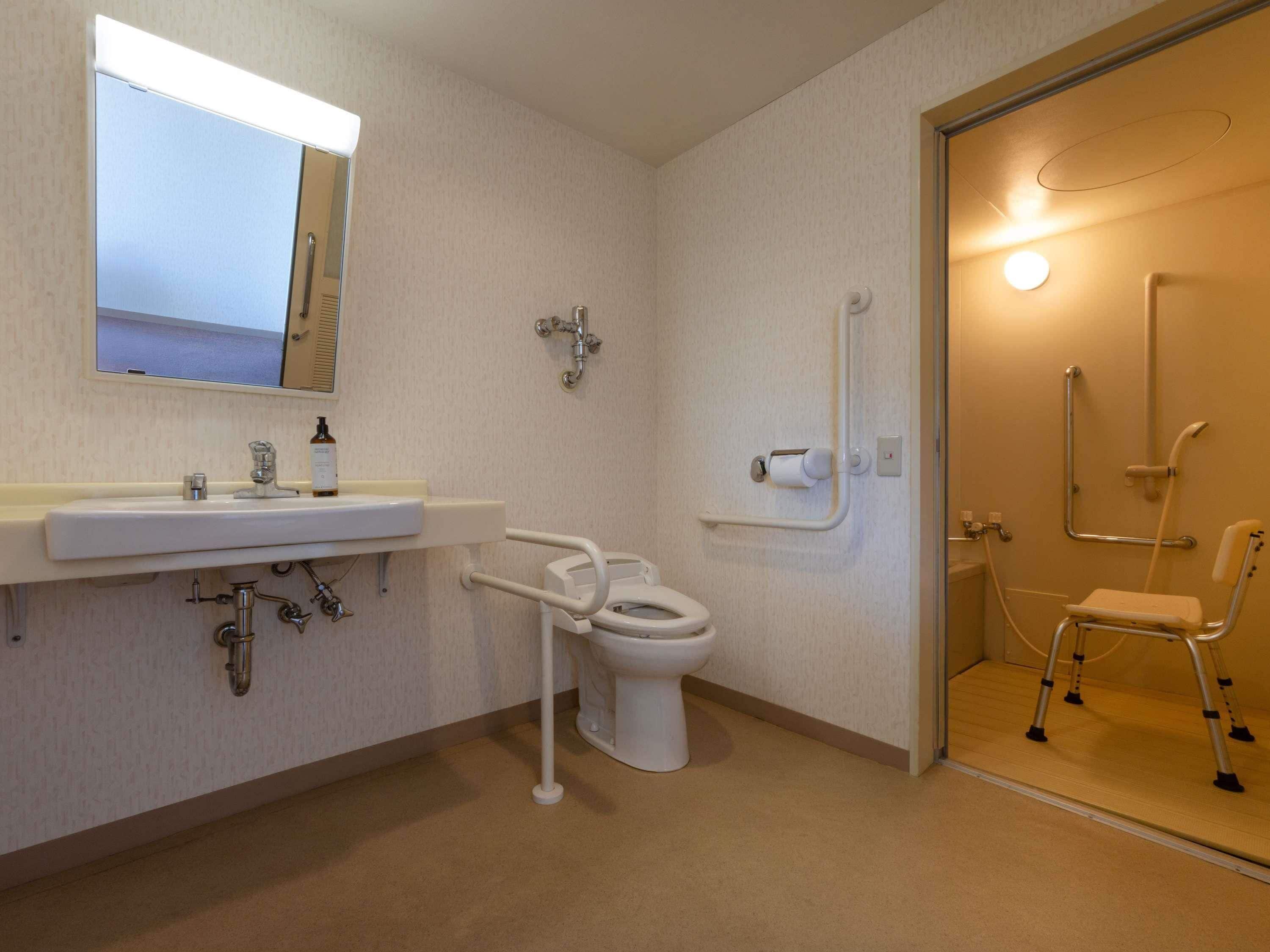 A bathroom with a sink, toilet, and shower chair.