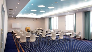 Un salón de conferencias con filas de mesas y sillas, una pizarra y un atril.