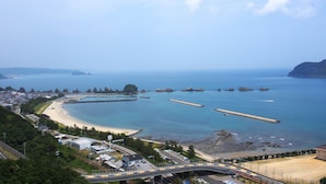 Un pueblo costero con playa, un puente y vista despejada al mar.