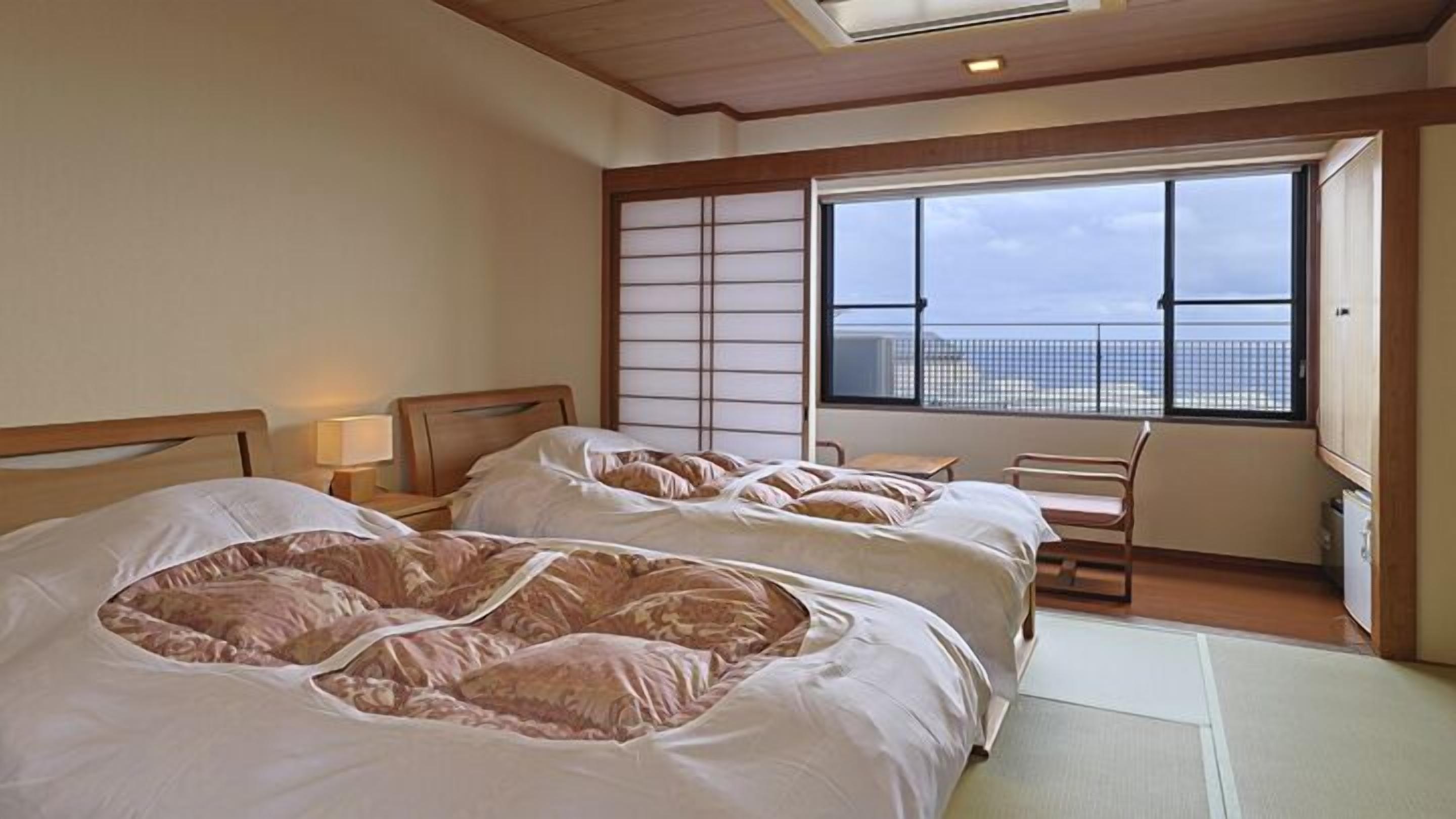 A hotel room with two beds, a large window, a view of the city, and a traditional Japanese shoji screen.