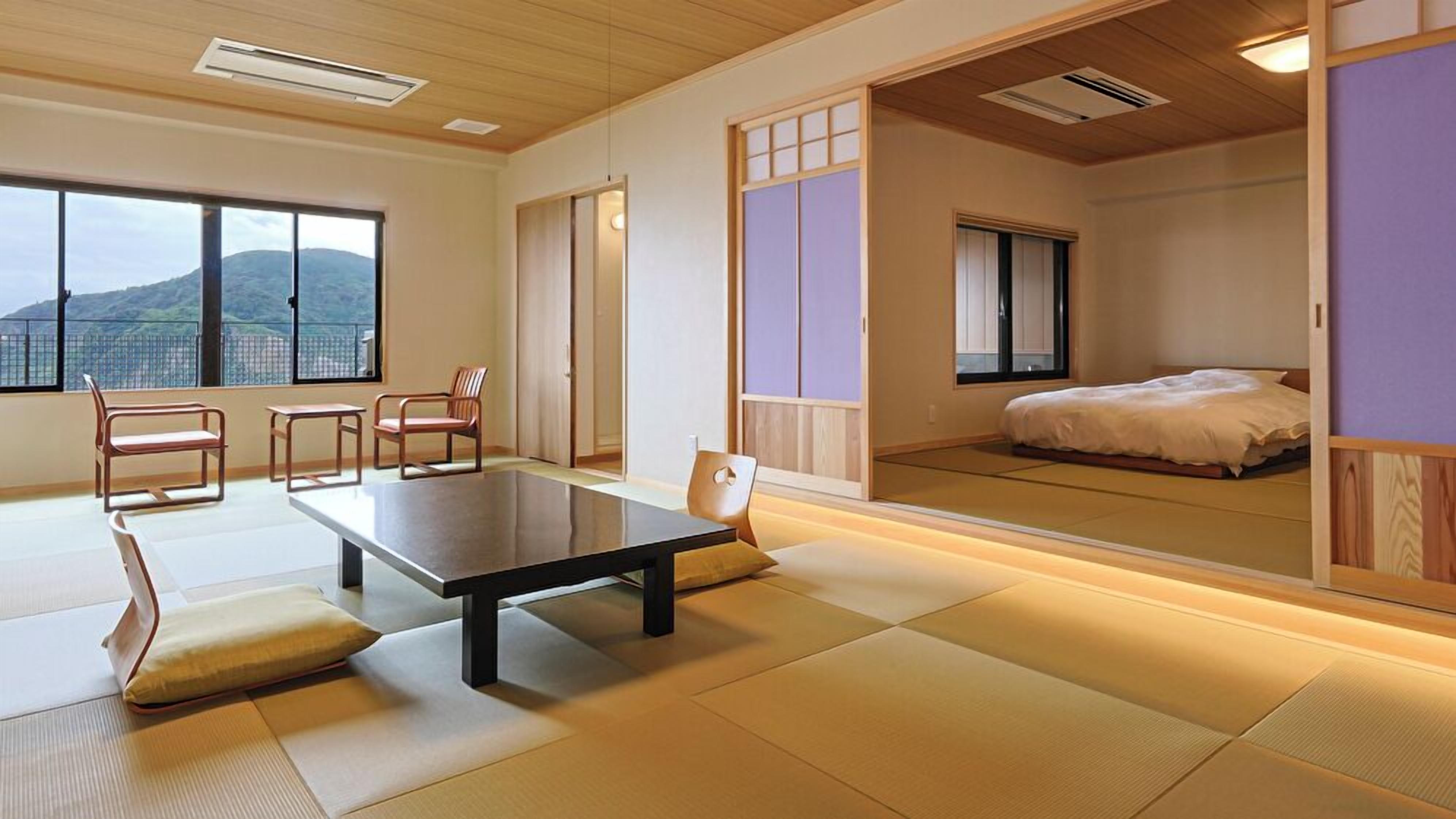 A traditional Japanese room with tatami flooring, a low table, chairs, a bed, and sliding doors.