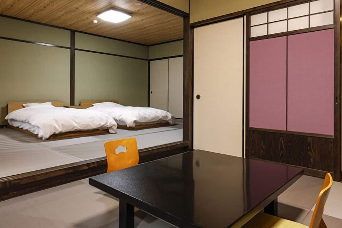 A traditional Japanese-style room with tatami flooring, a low wooden table, and a futon bed.