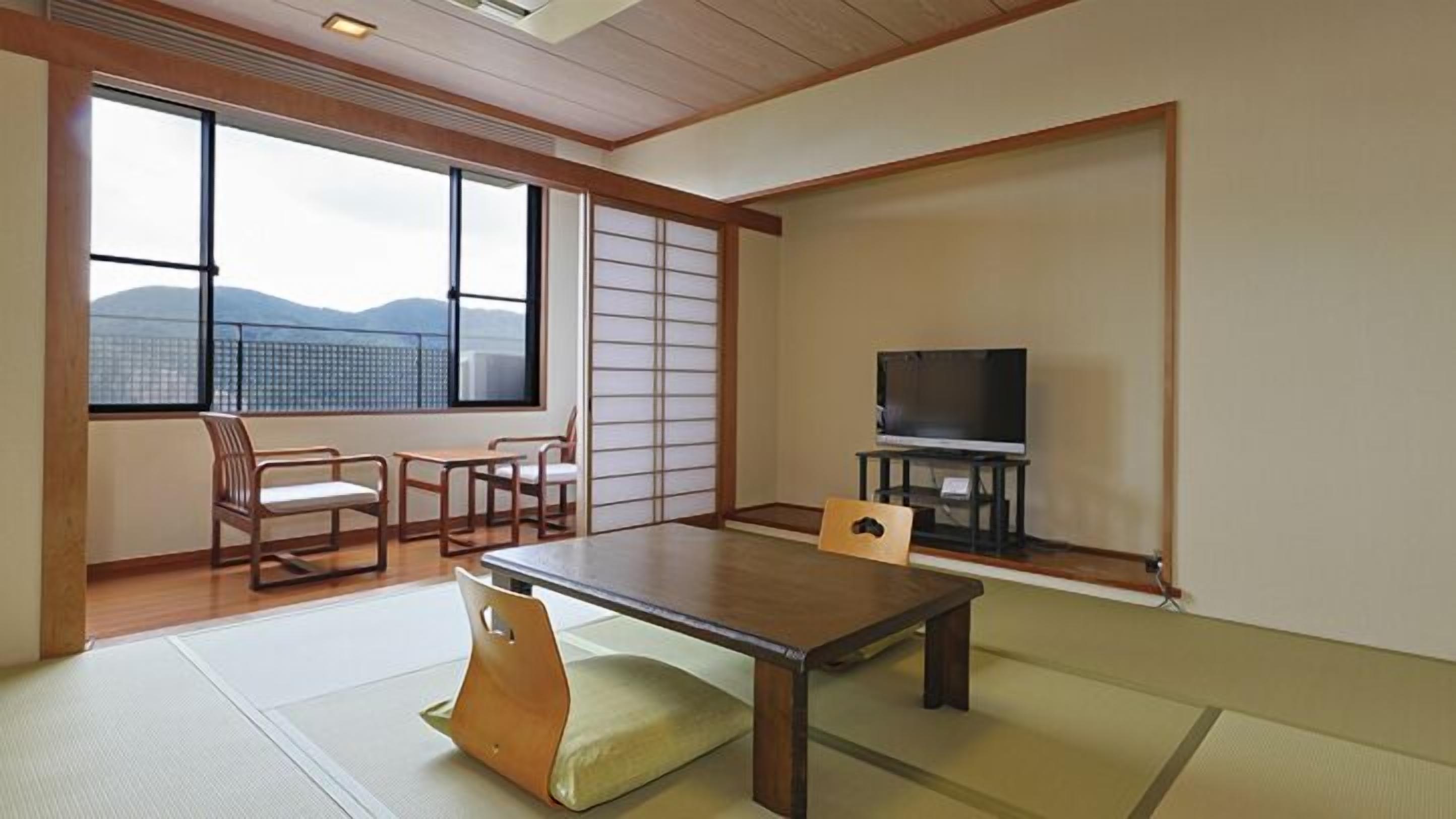 Et traditionelt japansk rum med tatamimåtter, et lavt bord, et fjernsyn og skydedøre.