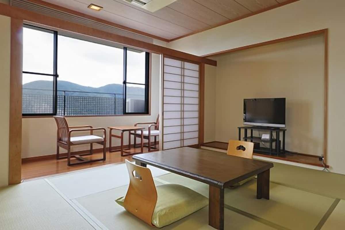 A traditional Japanese room with tatami flooring, a low table, a television, and sliding doors.