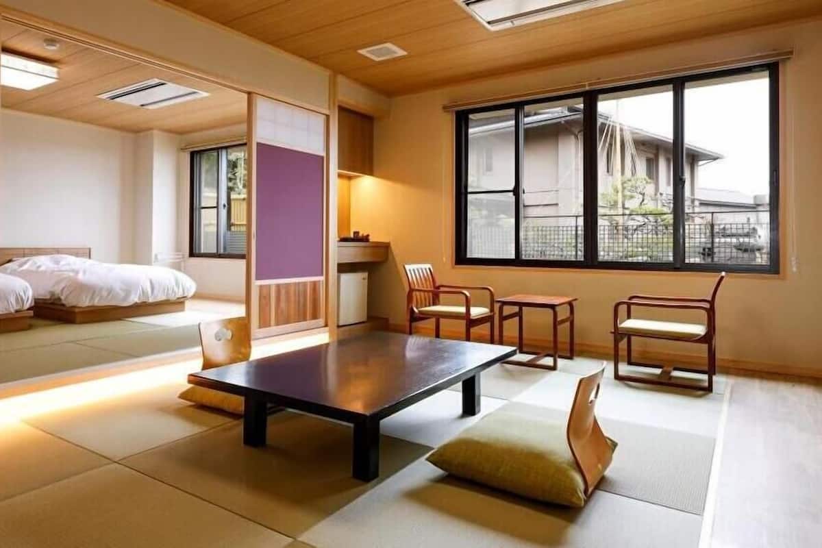 A traditional Japanese-style room with tatami flooring, a low table, and a bed with a futon.