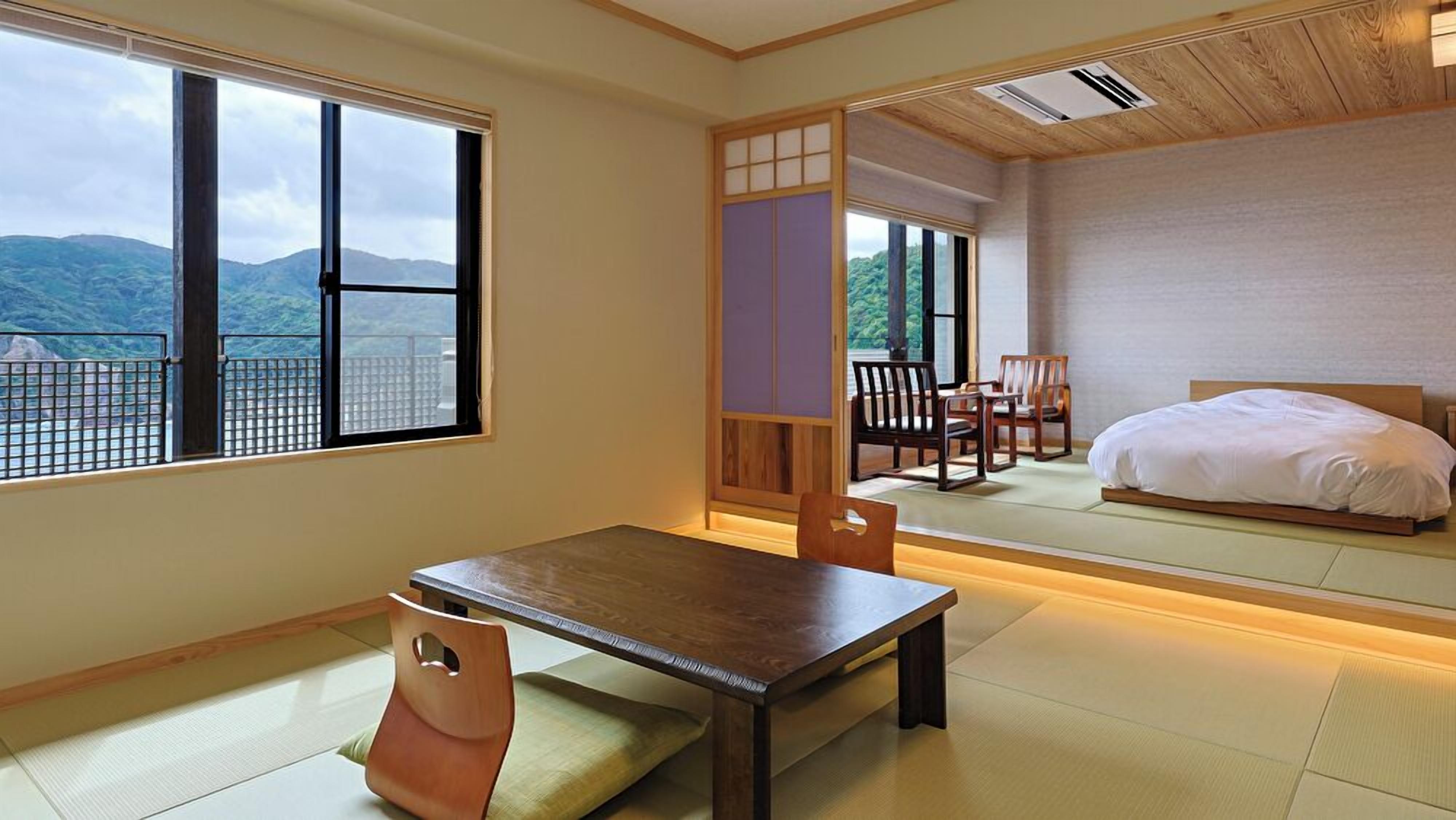 A traditional Japanese room with tatami flooring, a low table, and a bed.
