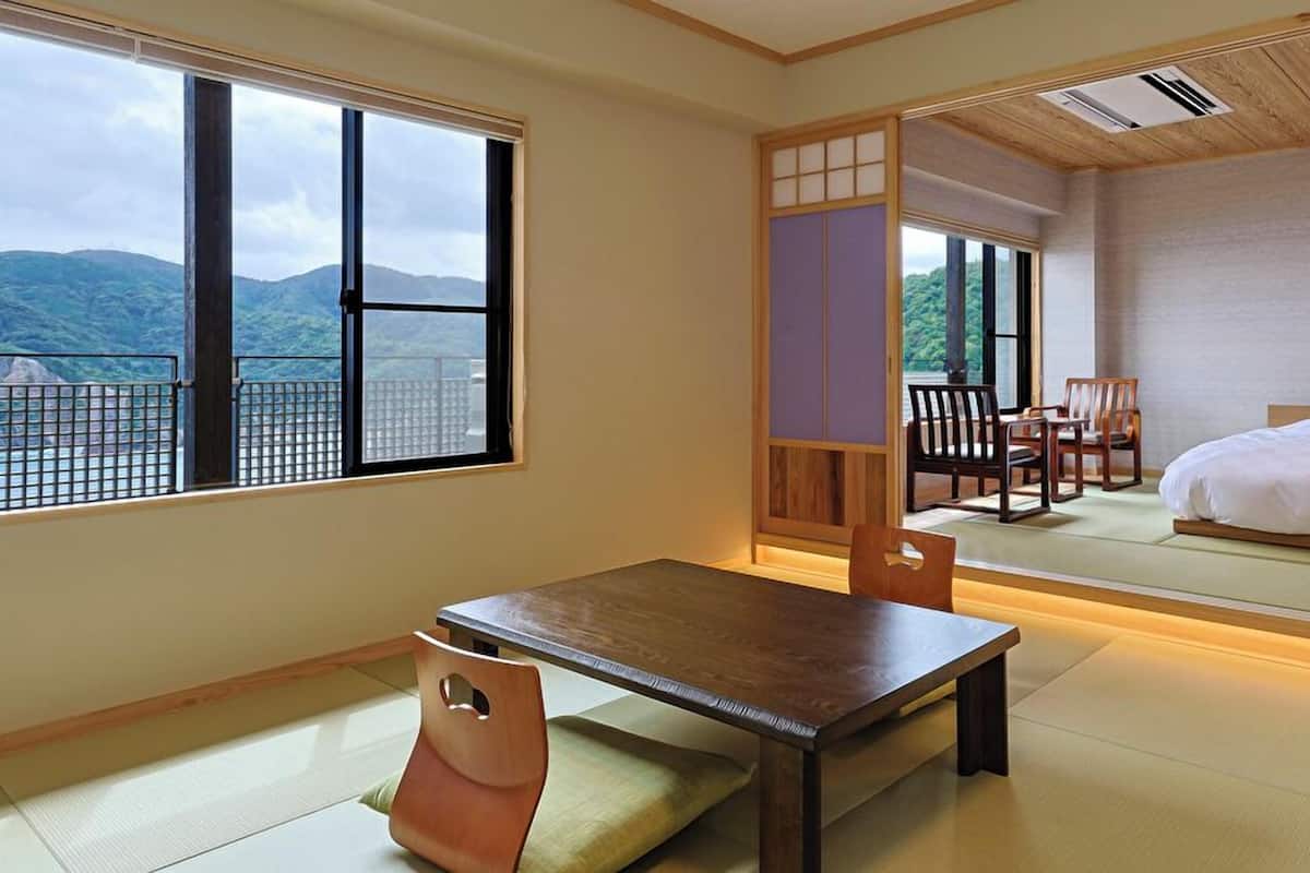A traditional Japanese room with tatami flooring, a low table, and a bed.