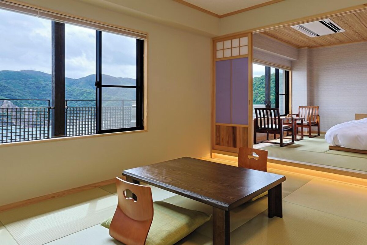 A traditional Japanese room with tatami flooring, a low table, and a bed.